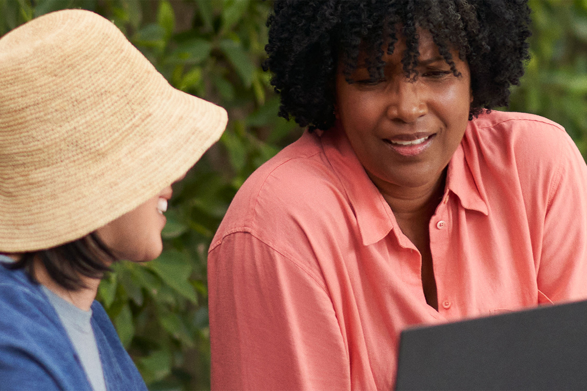 Duas mulheres a falar enquanto usam um portátil PCSpecialist com o Windows 11
