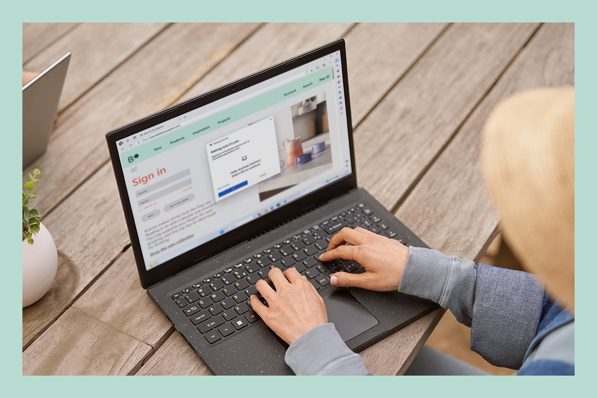 Uma mulher a usar um portátil e a segurança embutida do Windows 11.